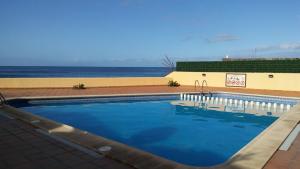 a swimming pool with the ocean in the background at APARTAMENTOS EL CIENO in La Playa Calera
