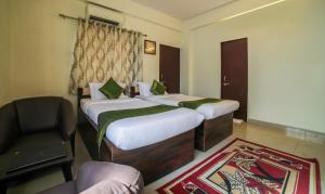 a hotel room with two beds and a chair at Treebo Trend Ivory House in Nagpur