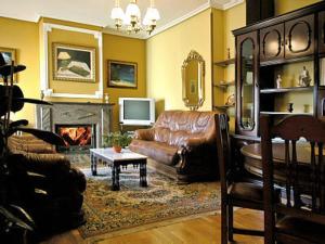 a living room with a leather couch and a fireplace at Casa Rural Sancho el Fuerte in Valtierra