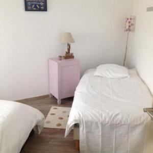 a bedroom with two beds and a dresser with a lamp at Villa des Sarcelles in Le Crotoy