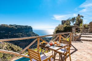 een tafel en stoelen op een patio met uitzicht op de oceaan bij Villa Amì in Scala