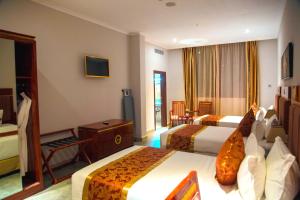 una camera d'albergo con due letti e una televisione di Tiffany Diamond Hotels LTD - Makunganya a Dar es Salaam