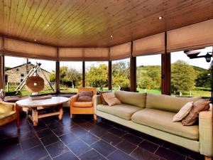 uma sala de estar com um sofá e uma mesa em Rustic house with sunroom em Petit-Thier