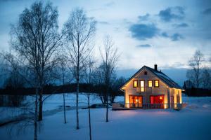 una pequeña casa con sus luces encendidas en la nieve en Vasekoja Holiday Center en Vahtseliina