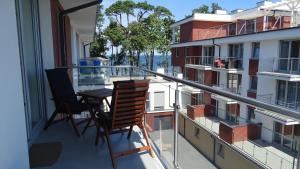 einen Balkon mit zwei Stühlen und einem Tisch darauf in der Unterkunft Apartament DeLux in Rewal