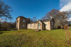 an old stone house on a grassy field at Evelix, The Old School House in Muir of Ord