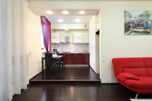 a living room with a red couch and a kitchen at PaulMarie Apartments on Lenina Avenue in Gomel