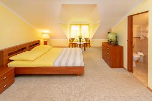 ein Schlafzimmer mit einem Bett und einem TV sowie ein Badezimmer in der Unterkunft Pensjonat Marynarski - Apartamenty in Darłówko
