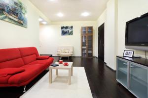 a living room with a red couch and a tv at PaulMarie Apartments on Lenina Avenue in Gomel