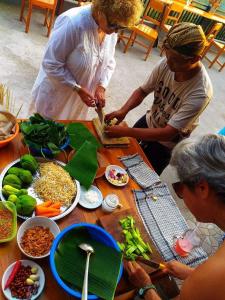 a group of people standing around a table with food at Nadya Homestay in Munduk