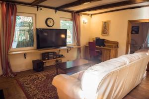 a living room with a white couch and a tv at Pamario Krašto Sodyba in Grumbliai