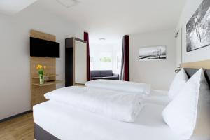 two beds in a hotel room with white sheets at K1 Hotel Willingen in Willingen