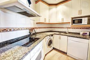 a kitchen with white cabinets and a washer and dryer at Puerto Marina Apartamento Exclusivo Benalmádena in Benalmádena