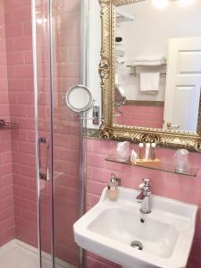 a pink bathroom with a sink and a mirror at Boutiquehotel Villa Rosenhof in Badenweiler +59 photos