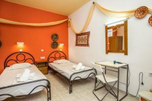 a room with two beds and a table and a mirror at Vickys Studios Faliraki in Faliraki