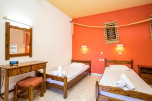 a room with two beds and a desk and a mirror at Vickys Studios Faliraki in Faliraki