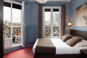 a bedroom with blue walls and a bed with windows at Hôtel Odessa Montparnasse in Paris