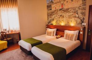a hotel room with two beds and a stone wall at Império do Rei Boutique Hotel in Castelo Branco