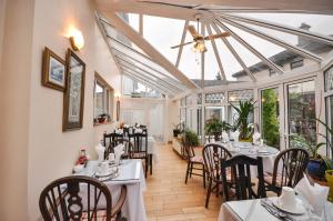 a dining room with tables and chairs and windows at Asgard Guest House in Galway