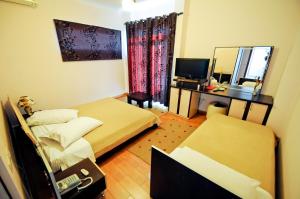 um quarto com 2 camas, uma secretária e um espelho. em Hotel Lubjana em Tirana