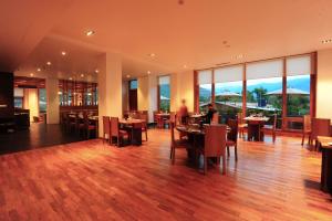um restaurante com mesas e cadeiras e janelas grandes em Norkhil Boutique Hotel & Spa em Thimphu
