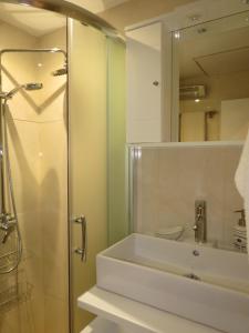 ein Bad mit einer Dusche, einem Waschbecken und einem Spiegel in der Unterkunft Nice studio next to the sea in Athen