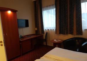 a hotel room with a bed and a desk with a television at Chesterfield Hotel in Trondheim