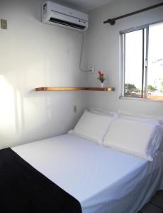 Cama blanca en habitación con ventana en Flat Pousada da Praia, en Natal