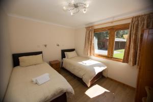 1 dormitorio con 2 camas y ventana en Invercauld Lodges, en Ballater