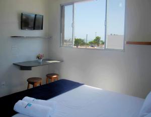 1 dormitorio con cama, ventana y mesa en Flat Pousada da Praia, en Natal