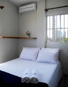 Una cama con sábanas blancas y dos toallas. en Flat Pousada da Praia, en Natal