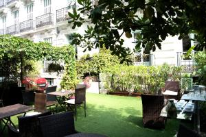 un jardin avec des tables et des chaises et un bâtiment dans l'établissement Hotel Villa Rivoli, à Nice