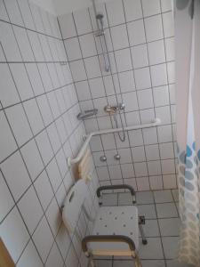 Baño de azulejos blancos con silla y aseo en Ferienhof Meyer Landhotel en Petershagen