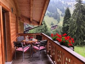 a wooden balcony with a table and chairs and flowers at Le Charme 9 in Morgins