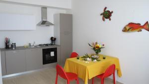 cocina con mesa amarilla y sillas rojas en Casa Nettuno, en Granelli