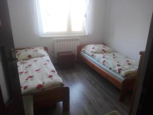twee bedden in een kleine kamer met een raam bij Agroturystyka u Tadka in Klęczany