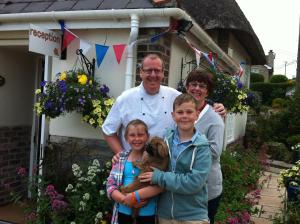 a family posing for a picture in front of a house at Yalbury Cottage in Dorchester