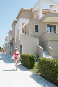 a woman walking down a sidewalk in front of a building at Niovi Boutique Apartments in Afitos