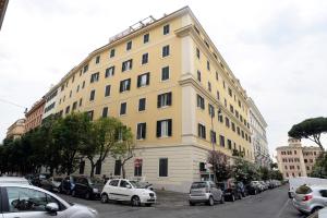 duży żółty budynek z samochodami zaparkowanymi na parkingu w obiekcie MECENATE DELUXE COLOSSEUM w Rzymie