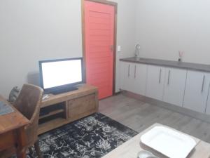 a kitchen with a red door and a desk with a television at The Coral Door in Vereeniging