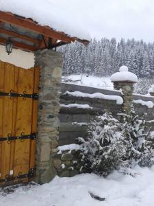 a stone wall with a wooden door in the snow at Під горою in Volovets