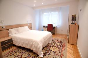 1 dormitorio con 1 cama y escritorio con silla roja en SANTANDER CENTRO, en Santander