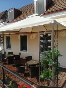 a patio with tables and chairs under an umbrella at Centrum Panzió in Szentendre