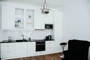 een witte keuken met witte kasten en een zwarte wastafel bij Apartament Skierniewice in Skierniewice