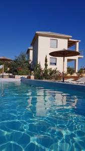 a swimming pool with a house and an umbrella at Luxurious villa at a unique spot in Agios Nikolaos