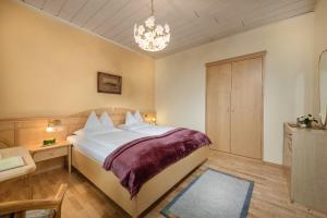 una camera con un grande letto e un lampadario a braccio di Hotel Alpenblick a Bad Gastein