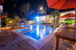 a swimming pool at night with a table and an umbrella at Hotel Port Louis in Mocoóca +115 photos