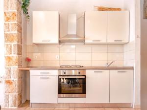 Una cocina con gabinetes blancos y una estufa. en Apartment Spila, en Ivan Dolac