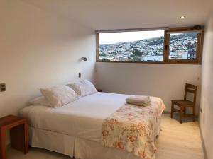 um quarto com uma cama e uma grande janela em Escalera al Puerto Guest House em Valparaíso