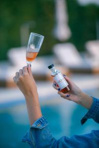 a woman holding up a glass of wine and a bottle at Niovi Boutique Apartments in Afitos